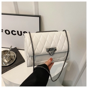 Detail of white quilted crossbody bag with metal twist lock and chain strap