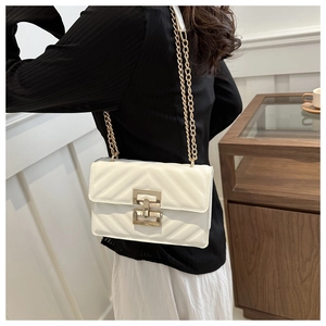 Close-up of a white V-quilted small square bag with golden chain and rotary lock
