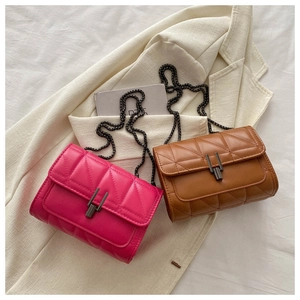Detail of quilted leather crossbody bags in fuchsia and caramel with chain straps