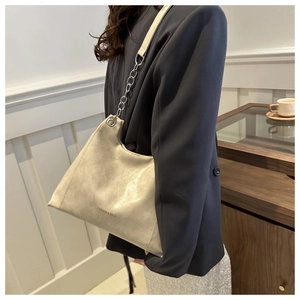 Detail of beige faux leather tote with silver chain strap and subtle logo print