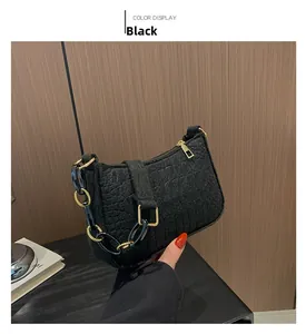Detail der schwarzen Schultertasche in Kroko-Optik mit Goldkette und Reißverschluss