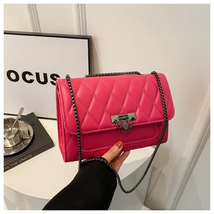 Detailed close-up of the rose pink quilted texture and black metal lock on this small bag