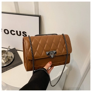 Detailed view of brown quilted crossbody bag with metal chain strap and twist lock closure