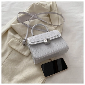 Mini white crocodile texture handbag shown with smartphone to demonstrate compact size