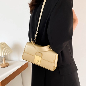 Elegant champagne gold shoulder bag with metallic handle and clasp worn with a black blazer