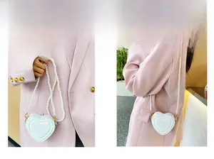 Detalle del mini bolso en forma de corazón con una correa de hombro decorativa de perlas