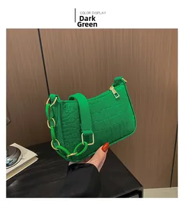 Details von dunkelgrüner Krokoprägung mit Goldreißverschluss und dekorativer Kette