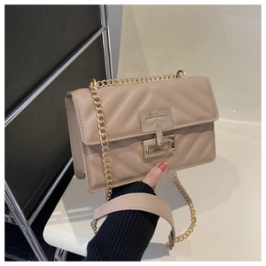 Close-up of beige crossbody bag with V-quilted texture and gold geometric twist lock