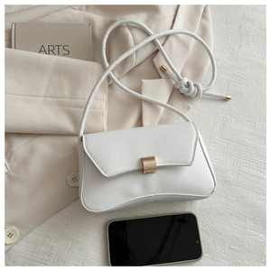Detailed close-up of a white leather handbag with gold metal clasp and knotted strap