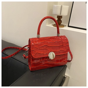 Close-up of bright red crocodile textured small square bag with silver round buckle