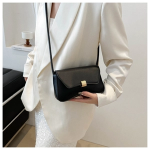 Detail of minimalist black leather crossbody bag with elegant golden metal clasp on a white suit