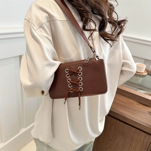 Sac à épaule marron en similicuir avec laçage porté par un mannequin dans un intérieur