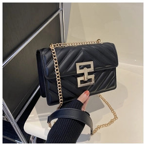 Close-up of black quilted leather crossbody bag with gold chain strap and metal clasp