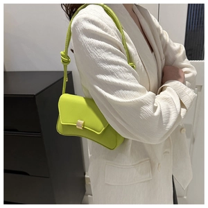 Detail of neon green leather shoulder bag with gold metal clasp and knot strap detail