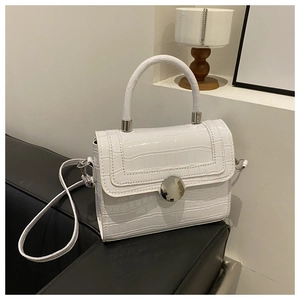 Detail of white crocodile embossed texture on crossbody bag with silver round lock