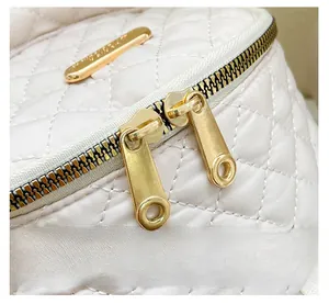 Detail of high-quality golden double zippers and quilting on a cream Oxford backpack
