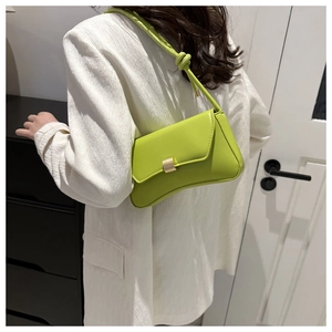 Detail of avocado green baguette bag with golden buckle and knotted strap on shoulder