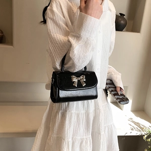 Elegant black patent leather mini crossbody bag with a silver bow clasp for women