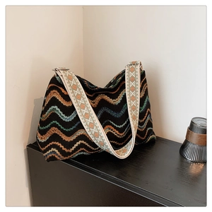 Détail d'un sac seau bohème en maille avec motifs à vagues et bandoulière tissée
