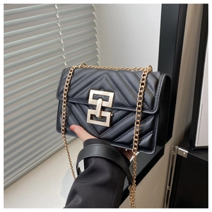 Detailed view of black quilted faux leather crossbody bag with golden chain and lock