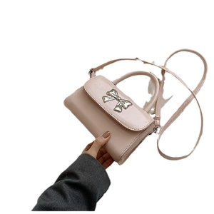 Pink faux leather crossbody bag with silver bow hardware and rounded top handle