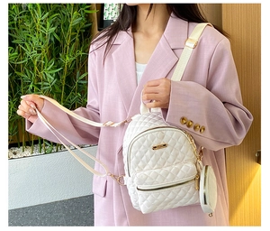 Close-up of white quilted mini backpack with gold hardware and matching round coin purse
