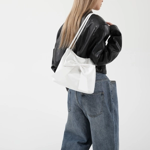 Weiße Oversize-Schleifen-Einkaufstasche für Damen, getragen von einem Modell im urbanen Stil