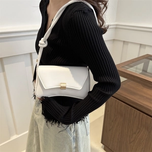 White minimalist leather underarm bag with gold metal clasp and knotted shoulder strap