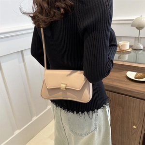 Retro beige leather crossbody bag with a matte gold clasp shown in a lifestyle setting