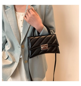 Détail du sac à main noir matelassé avec fermoir argenté porté sur veste