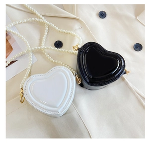 Detalle de bolsos bandolera con forma de corazón en charol y correas de perlas de lujo