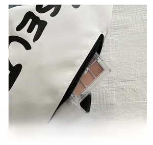 Détail du sac de sport blanc montrant la poche latérale avec une palette de maquillage