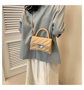 Détail du sac bandoulière matelassé crème avec fermoir métallique et base incurvée chic