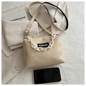 Detail of a beige PU leather crossbody bag with chain handle and fashion label