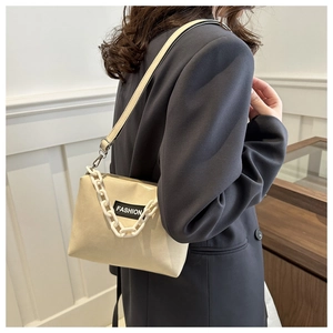 Detail view of beige matte leather shoulder bag with chunky white chain and fashion patch