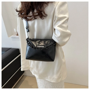Detail of black leather crossbody bag with chunky chain and adjustable strap