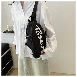 Détail du sac de poitrine en toile noire avec lettrage TGSEU blanc et sangle réglable