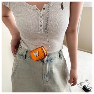 Detail of orange metallic mini crossbody bag with silver butterfly and chain strap