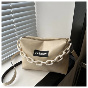 Detailed macro view of cream PU leather handbag with white chain and fashion patch