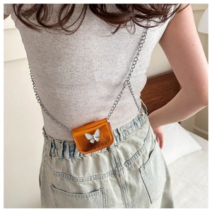 Detail of bright orange mini bag with white butterfly motif and silver chain strap