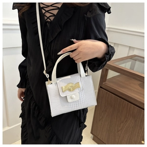 Détail du sac blanc à motif crocodile avec garniture métallique dorée ondulée