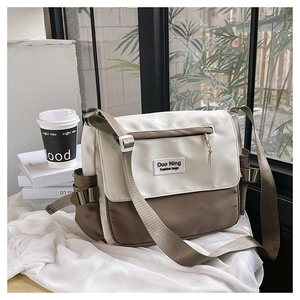 Détail du sac bandoulière en toile sur un bureau avec poche latérale et rabat