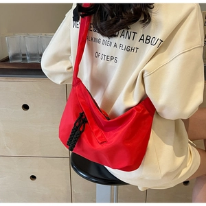 Detail of red oversized crescent crossbody bag with black braided zipper puller and nylon finish