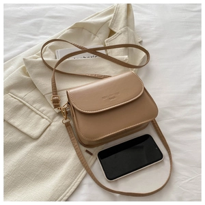 Macro detail of khaki PU leather crossbody bag with flap and gold hardware accents