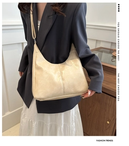Detailed view of cream leather crescent bucket bag featuring reinforced stitching and strap