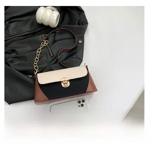 Detail of color-block baguette bag featuring croc-texture flap and golden press lock