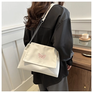 Detail view of pink butterfly embroidery and metal chain strap on off-white bag