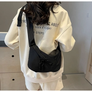 Back view of a black large-capacity nylon crescent bag with wide shoulder strap worn by model
