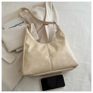Detail of apricot minimalist tote bag with pebble texture, styled on a white blazer
