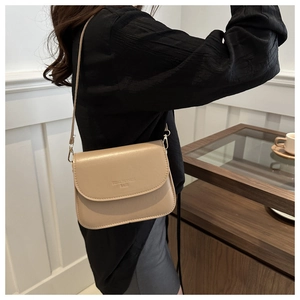 Detail of the chic beige crossbody bag featuring an elegant flap with logo lettering